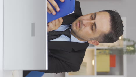 Vertical-video-of-Home-office-worker-man-examining,-analyzing-documents.